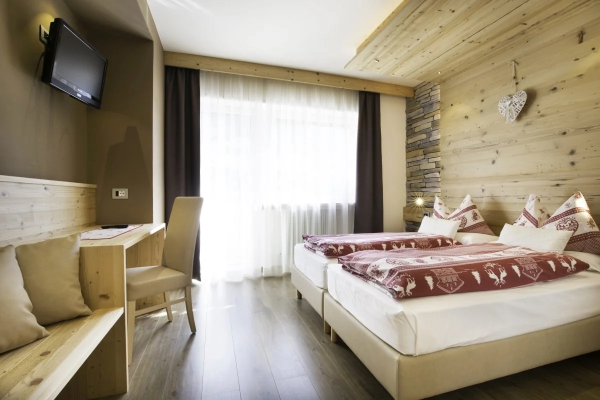 Camera New Design con letto, parete in legno chiaro e finestra sul balcone