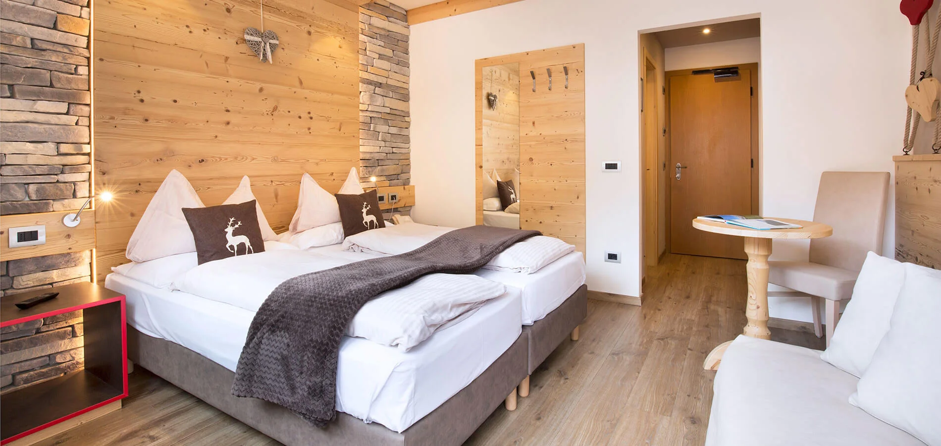 Camera dell’Hotel Azola con arredi in legno e divano